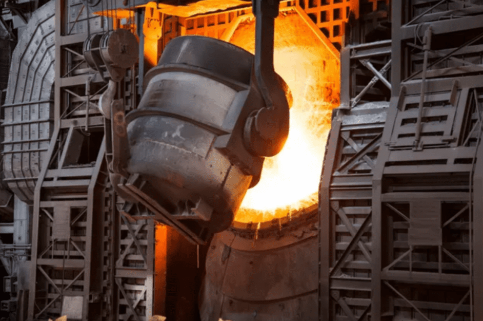 Molten metal being poured from a large ladle in a steel mill.