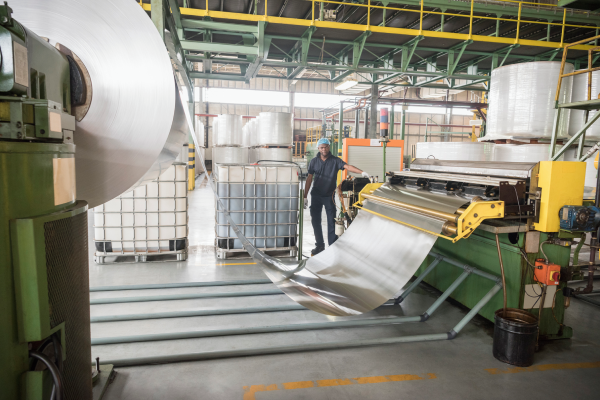 Workers handling large metal sheets in an industrial factory.