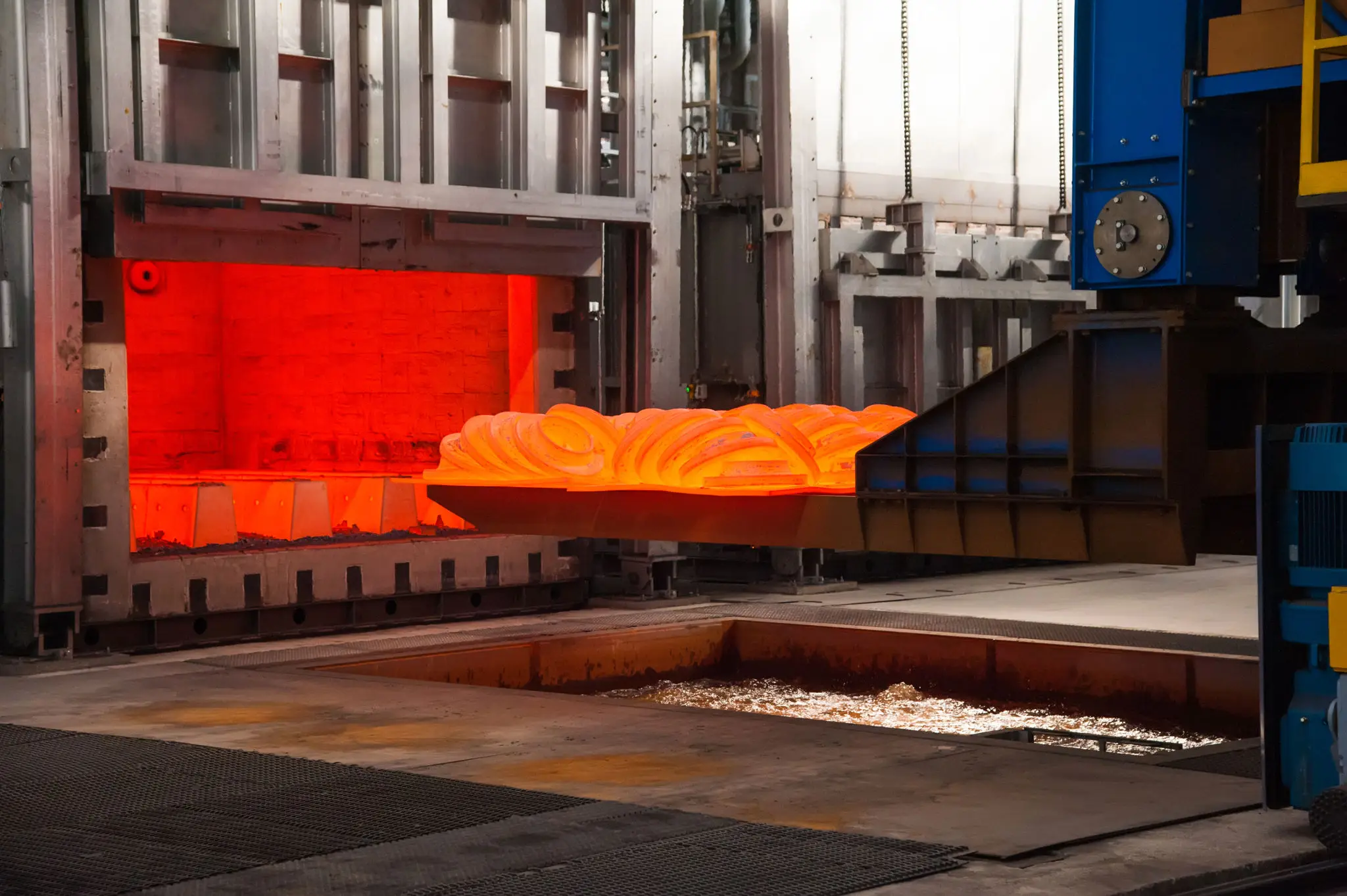 Glowing hot metal being processed in an industrial furnace.